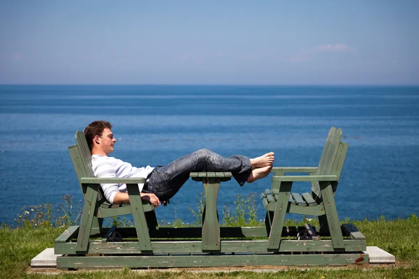 Junger Mann sitzt am Strand — Stockfoto