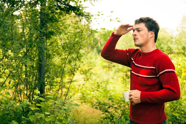 Jonge mens in de natuur met een mok van koffie — Stockfoto