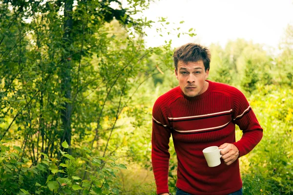 Ung man i naturen med en mugg kaffe — Stockfoto