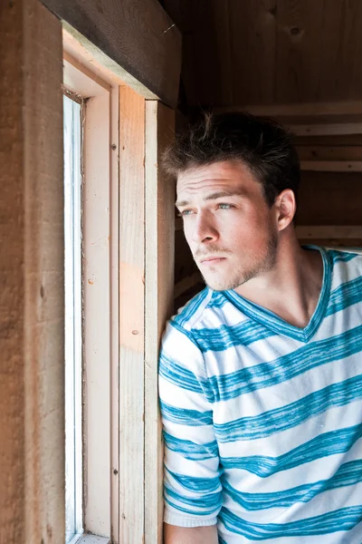 Young man looks out the window — Stock Photo, Image