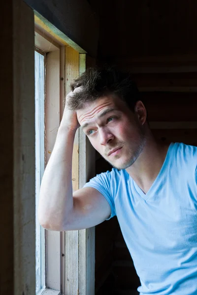 Young man looks out the window — Stock Photo, Image