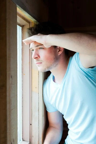 Young man looks out the window — Stock Photo, Image