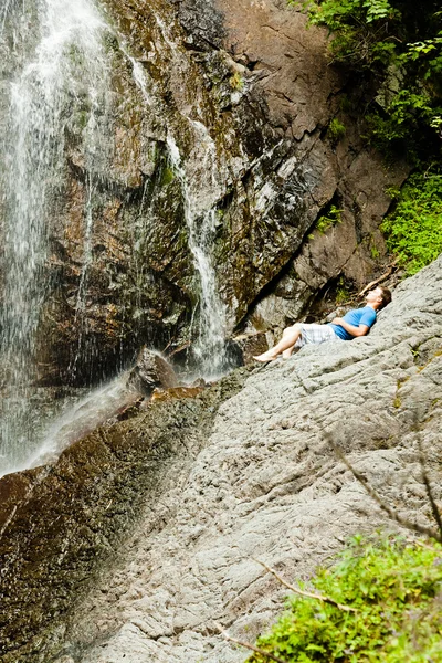 Young man near a waterfall — Stock Photo, Image