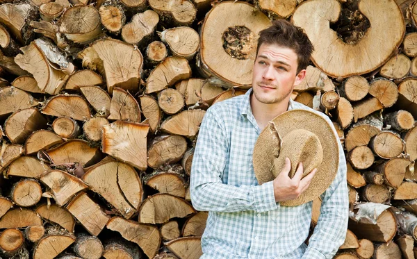 Mladý muž v slaměný klobouk na pozadí dřeva — Stock fotografie