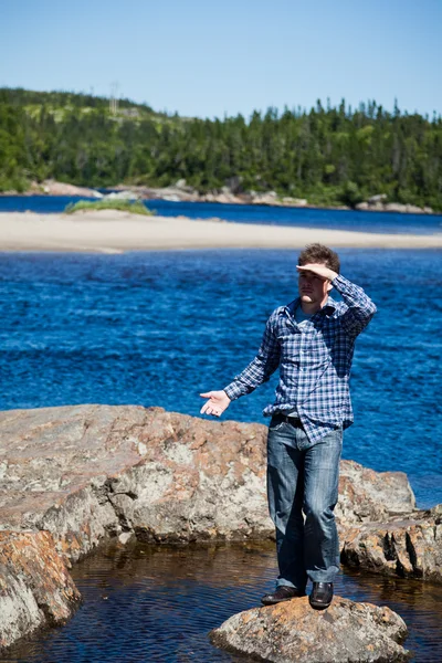 年轻男子站在一块岩石上 — 图库照片
