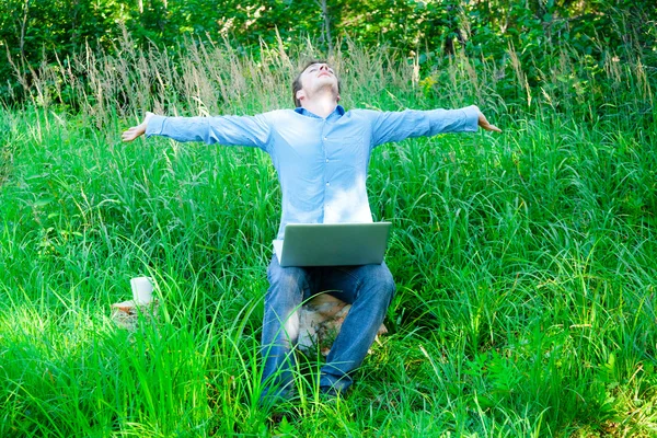 Jonge man buiten met een kop en laptop — Stockfoto