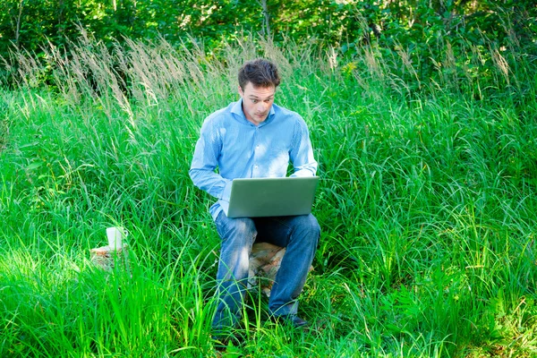 Jovem ao ar livre com uma xícara e laptop — Fotografia de Stock