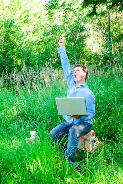 Hombre joven al aire libre con una taza y un ordenador portátil —  Fotos de Stock