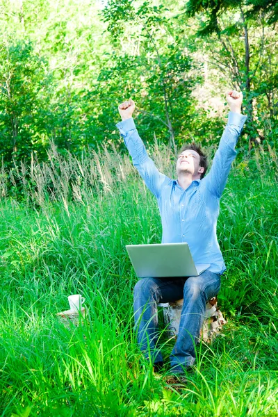 Hombre joven al aire libre con una taza y un ordenador portátil — Foto de Stock