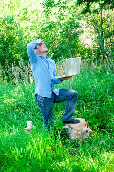 Jovem ao ar livre com uma xícara e laptop — Fotografia de Stock