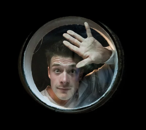 The young man looks the porthole — Stock Photo, Image