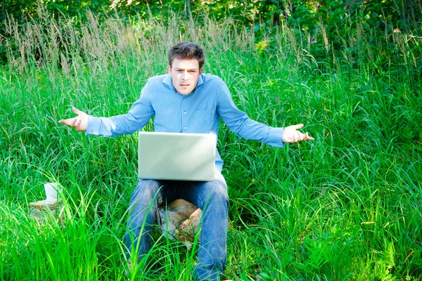 Jovem ao ar livre com uma xícara e laptop — Fotografia de Stock