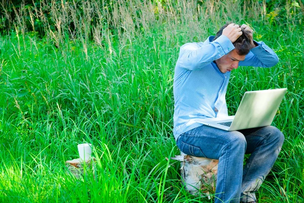 Jovem ao ar livre com uma xícara e laptop — Fotografia de Stock