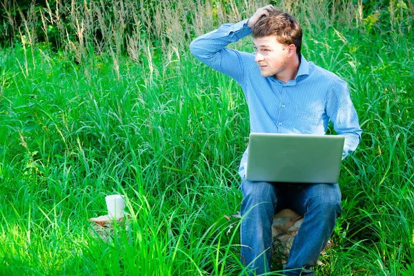 Jovem ao ar livre com uma xícara e laptop — Fotografia de Stock