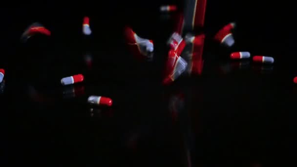 Cápsulas de pastillas que caen sobre vidrio negro — Vídeos de Stock