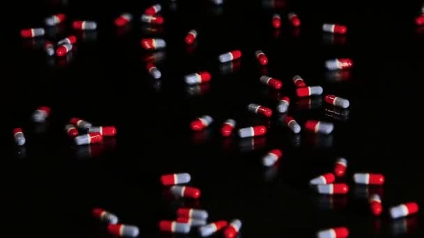 Капсулы таблеток скольжения на черном стекле - изолированные — стоковое видео