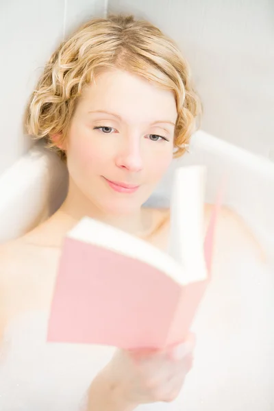 Молода жінка розслабляється і читає книгу в лазні — стокове фото