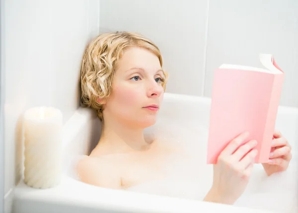 Mujer joven relajándose y leyendo un libro en el baño — Foto de Stock