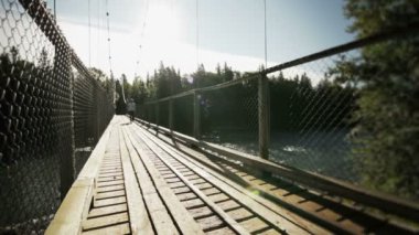 bir asma köprü üzerinde yürüyen genç yetişkin adam