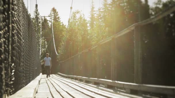 Jeune homme adulte marchant sur un pont suspendu — Video