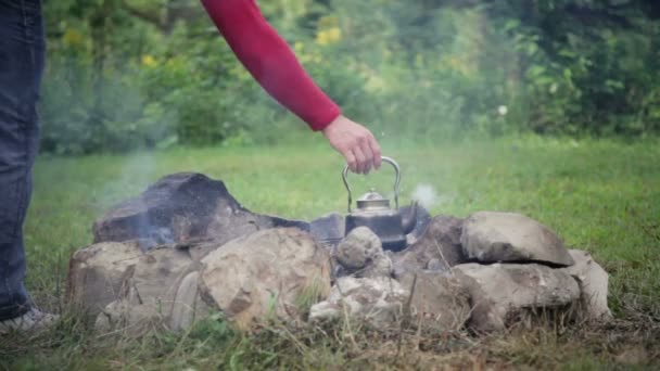 Young man puts the kettle on the fire — Stock Video