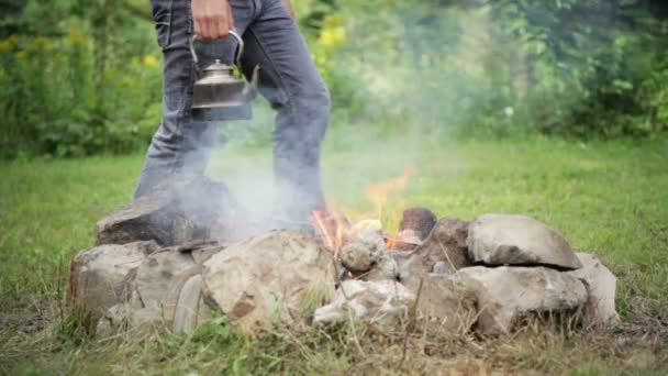 Young man puts the kettle on the fire — Stock Video