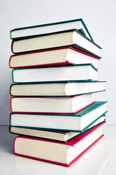 Stack of books on white reflective surface — Stock Photo, Image