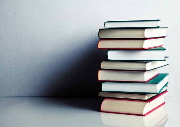 Stack of books on white reflective surface — Stock Photo, Image