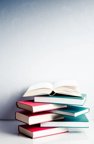 Open boek op een groene en rode stapel boeken — Stockfoto