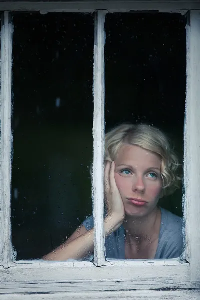 无聊的女人正看着靠窗的阴雨天气 — 图库照片
