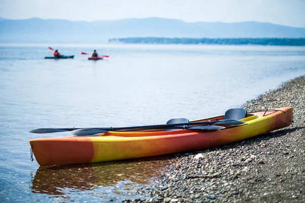 Caiaque na costa do mar com kayakers no fundo — Fotografia de Stock