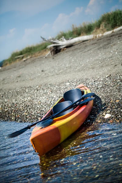 Kayak naranja y amarillo con remos en la orilla del mar — Foto de Stock