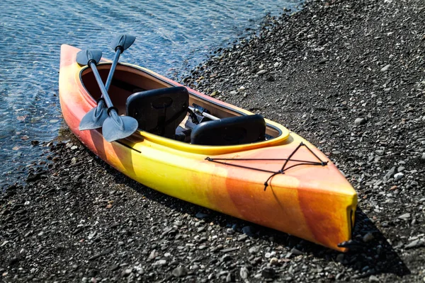 Kayak naranja y amarillo con remos en la orilla del mar — Foto de Stock