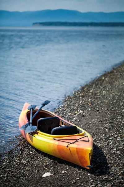 Kayak naranja y amarillo con remos en la orilla del mar —  Fotos de Stock