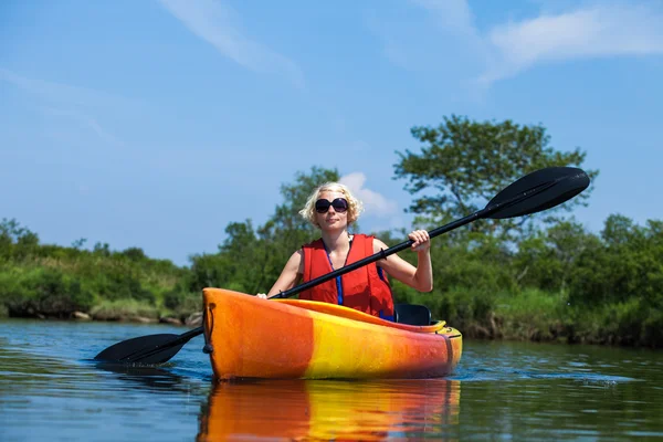 Kvinna med säkerhet västen kajakpaddling ensam på en lugn flod — Stockfoto