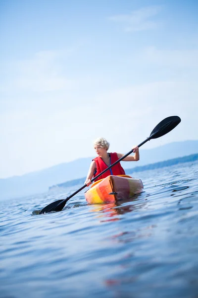 Vrouw met veiligheid vest kajakken alleen op een kalme zee — Stockfoto