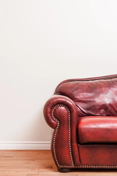 Luxuoso sofá de couro vermelho na frente de uma parede em branco — Fotografia de Stock