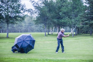 yağmurlu bir günde swigning fairway in üzerinde golfçü
