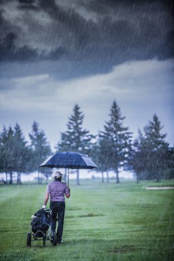Bir yağmurlu günde golf sahası bırakarak golfçü