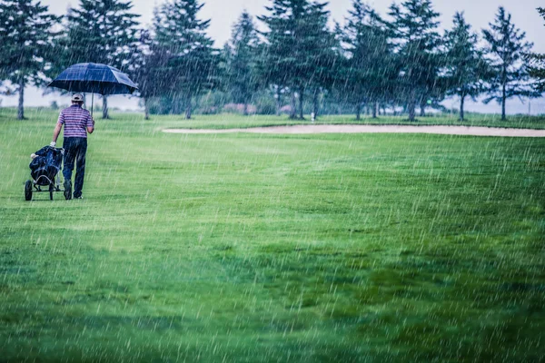 Golfista na deštivý den odchodu golfové hřiště — Stock fotografie