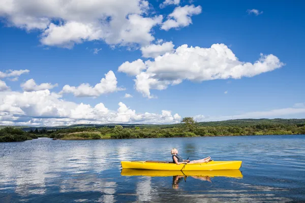 Rio calmo e mulher relaxando em um caiaque — Fotografia de Stock