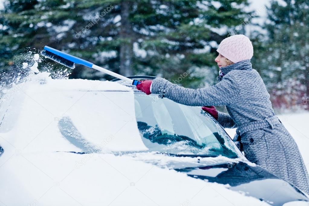 Woman Removing Snow from a Car with a Broom