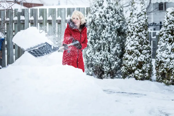 女性が彼女の駐車場の雪かき — ストック写真