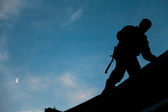 Bauunternehmer in Silhouette arbeitet auf einem Dach
