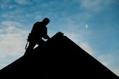 Bauunternehmer in Silhouette arbeitet auf einem Dach