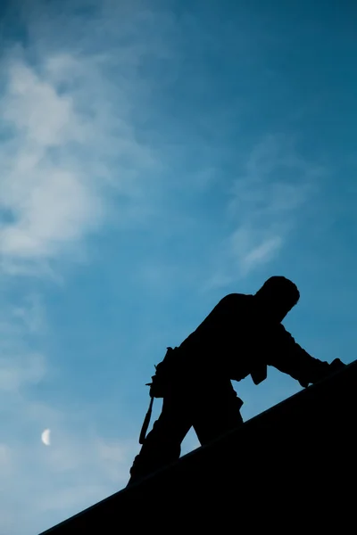 Empreiteiro em Silhouette trabalhando em um telhado Top — Fotografia de Stock