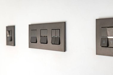 Beyaz duvarda modern ışık düğmeleri siyah renkte.