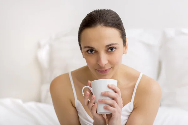 Woman in bed drinking tea