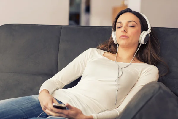 Mujer relajada escuchando música en el sofá en casa — Foto de Stock