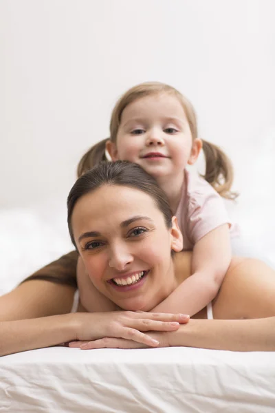 Daughter hugging her mother on the white bed — Stock Photo, Image